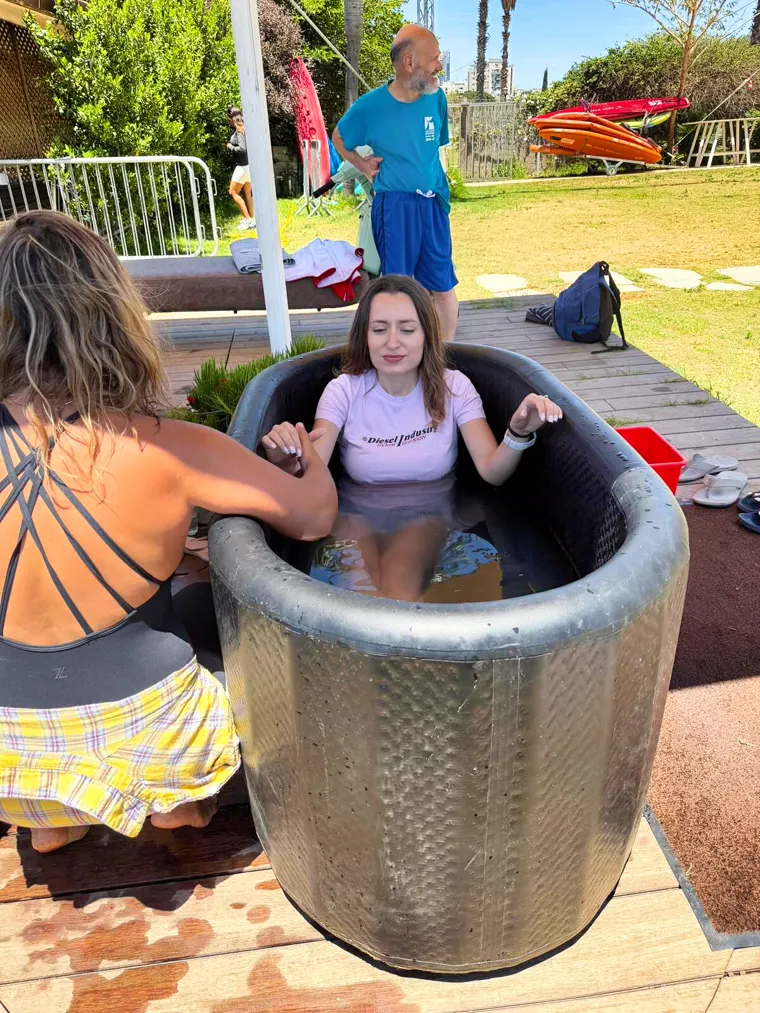 משתתפת יושבת באמבטיית הקרח ומחייכת